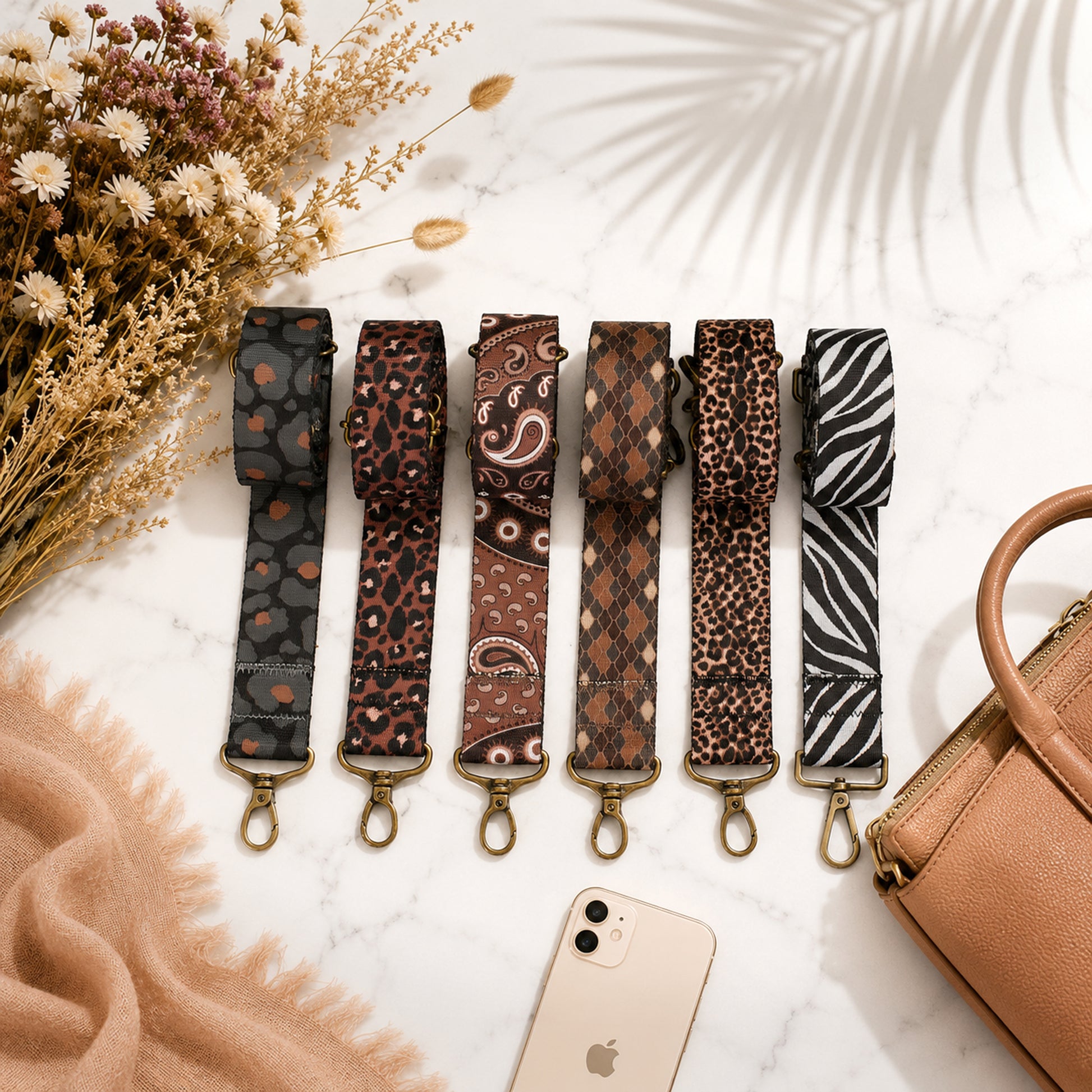 Set of patterned strap options on a marble surface with a phone and handbag.