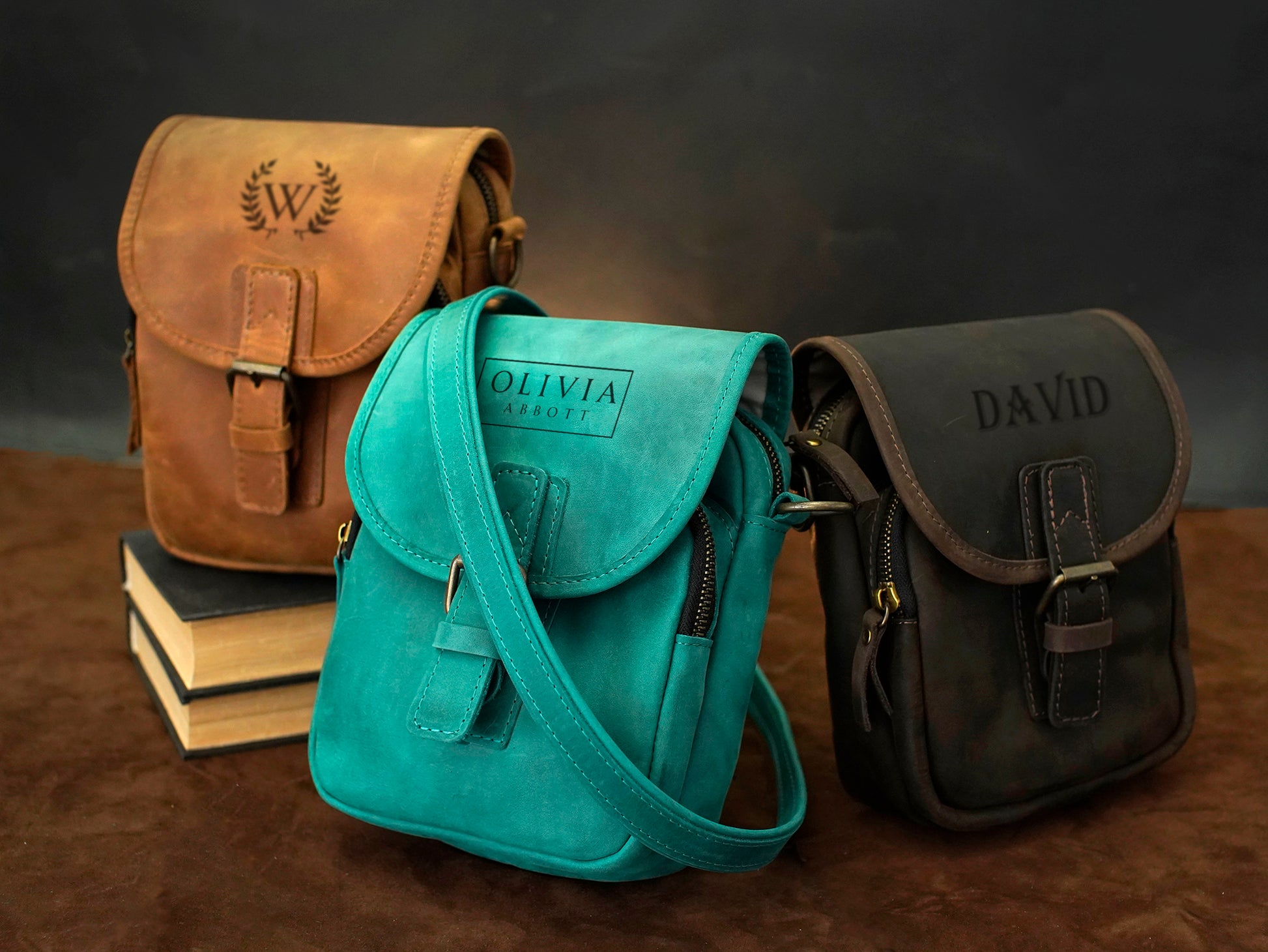 Three leather bags with personalized names on a dark background