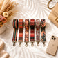 Set of patterned strap extensions on a light surface with a phone and flowers.
