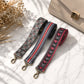 Three patterned bag straps on a light surface with a beige handbag and dried flowers.