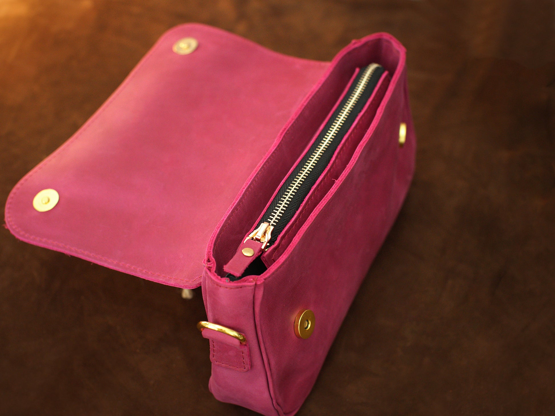 The leather crossbody pouch in use outdoors, warm earthy tones