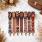 Set of patterned strap options on a textured surface with dried flowers and a brown bag.