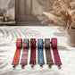 Set of colorful patterned dog leashes on a marble surface with a vase of dried flowers in the background.