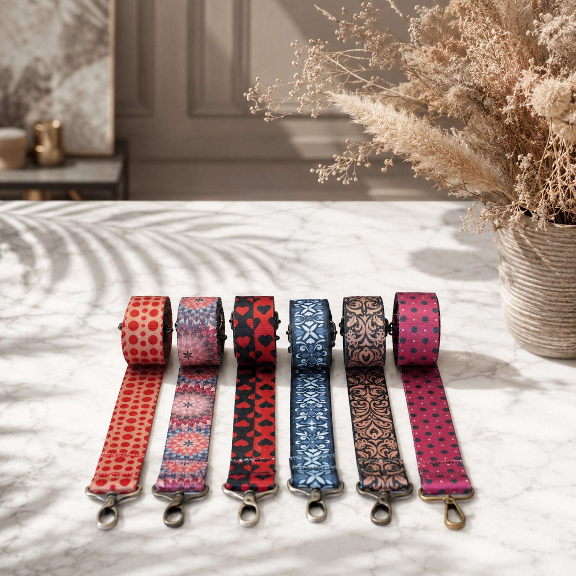 Set of colorful patterned dog leashes on a marble surface with a vase of dried flowers in the background.