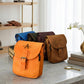 Four bags in different colors on a marble surface with a shelf in the background.