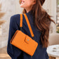 Woman wearing an orange crossbody bag with a blurred indoor background