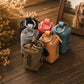 Five small milk carton-shaped keychains or bag charms in different colors are arranged on a wooden surface. The visible names printed on the cartons are Milo, Fun, and Chocochip.