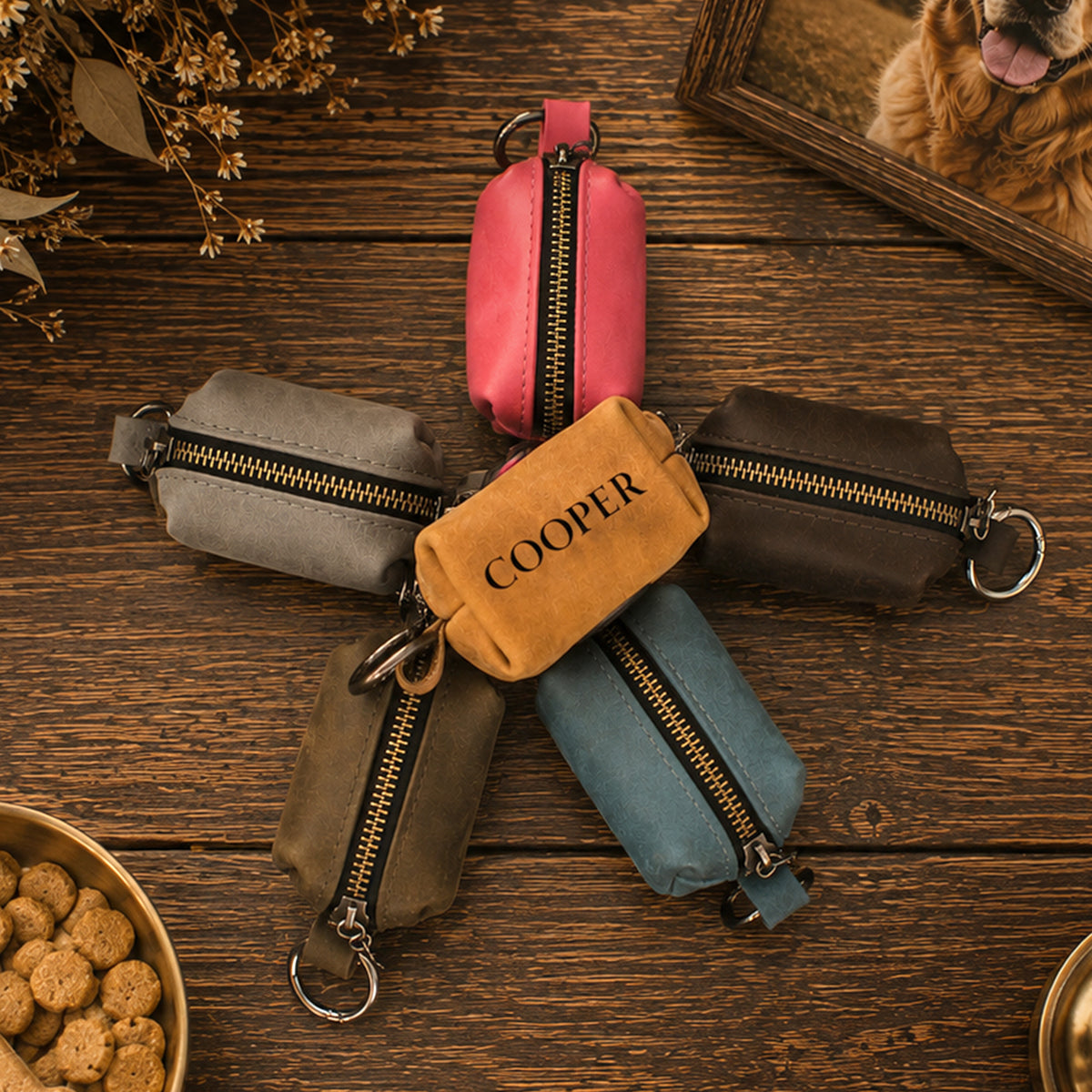 Five small zippered pouches arranged in a star shape on a rustic wooden table. The center pouch is tan and printed with the word "COOPER" in black.