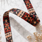 Geometric patterned belt on a marble surface with dried flowers.