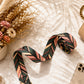 Patterned fabric roll on a textured surface with flowers and phone in the background