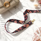 Floral patterned lanyard with gold clasp on a marble surface