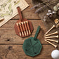 Two personalized leather golf accessories on a rustic wooden table: a brown octagonal tag holding six wooden tees and a green octagonal tag engraved with the name GEORGE and crossed golf clubs. Additional tees, a golf ball, dried flowers, and a map sheet are arranged around them.