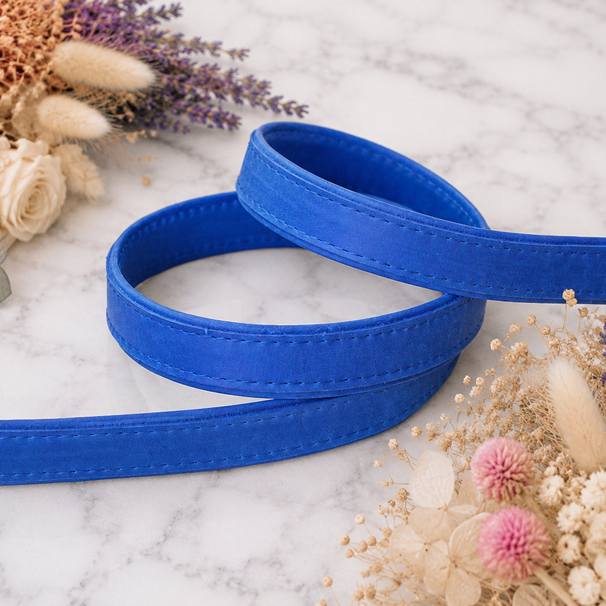 Blue belt on a marble surface with dried flowers