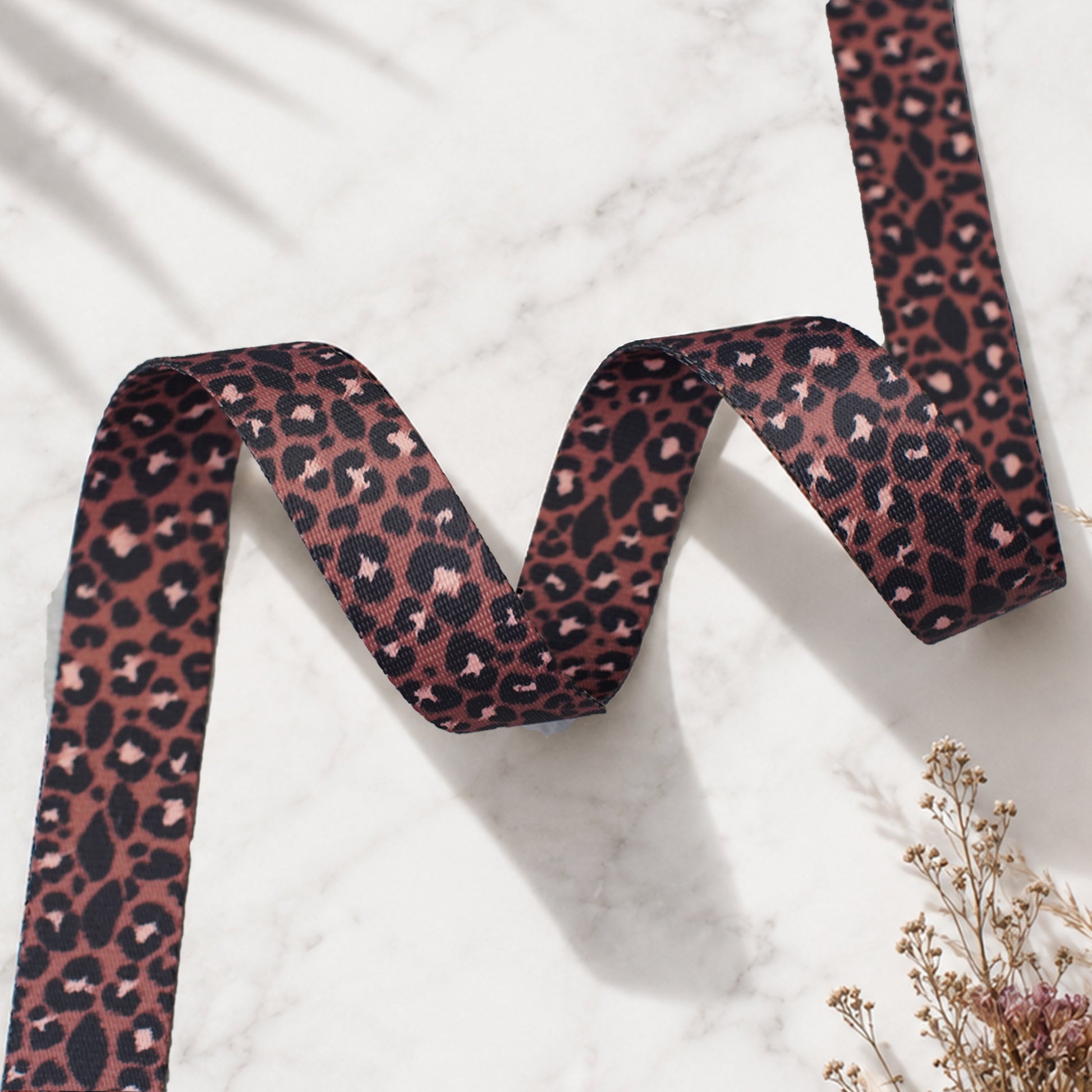 Leopard print ribbon on a marble surface with a plant in the corner