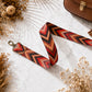 Decorative strap with geometric pattern on a marble surface with dried flowers.