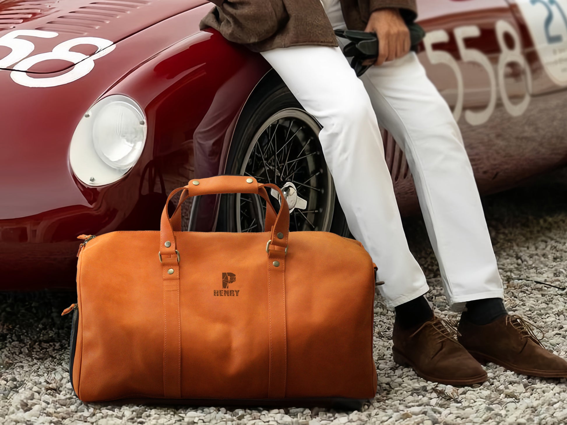 Orange duffel bag with a brand logo in front of a red vintage car.