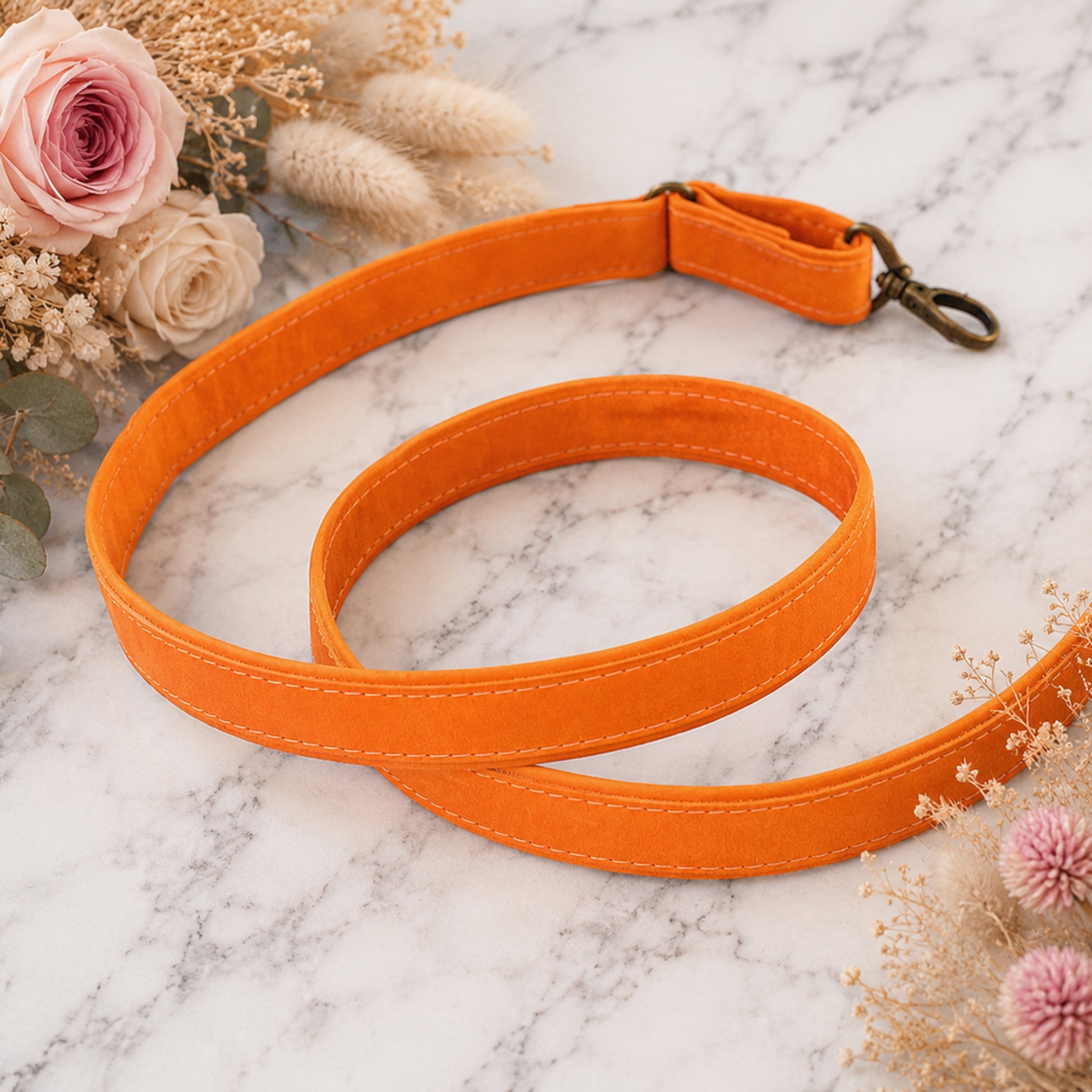 Orange dog leash on a marble surface with flowers