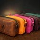 Row of colorful leather bags with visible brand logo on a dark background