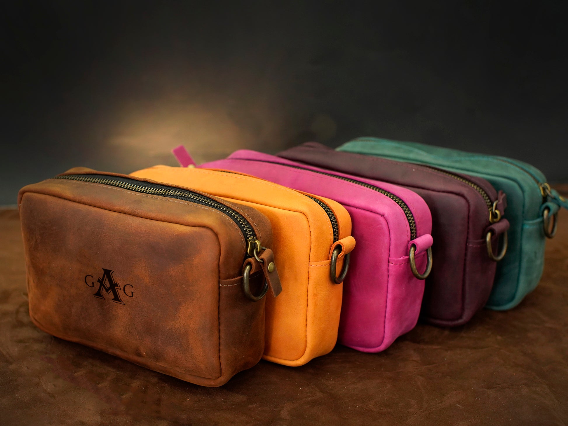 Row of colorful leather bags with visible brand logo on a dark background