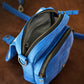 Blue bag with gold zippers on a wooden surface