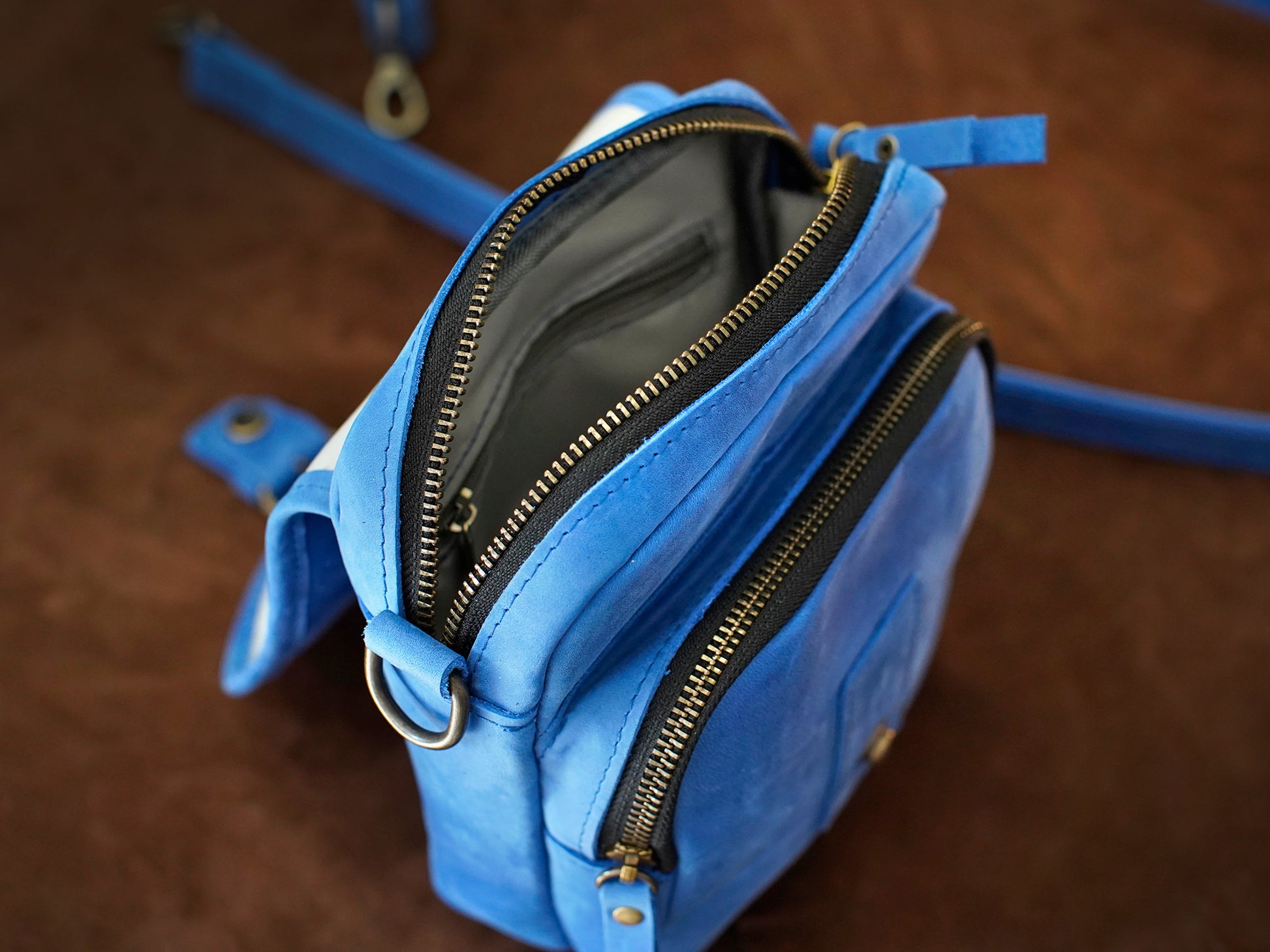 Blue bag with gold zippers on a wooden surface
