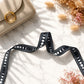 Black polka dot strap with beige handbag on marble surface with dried flowers