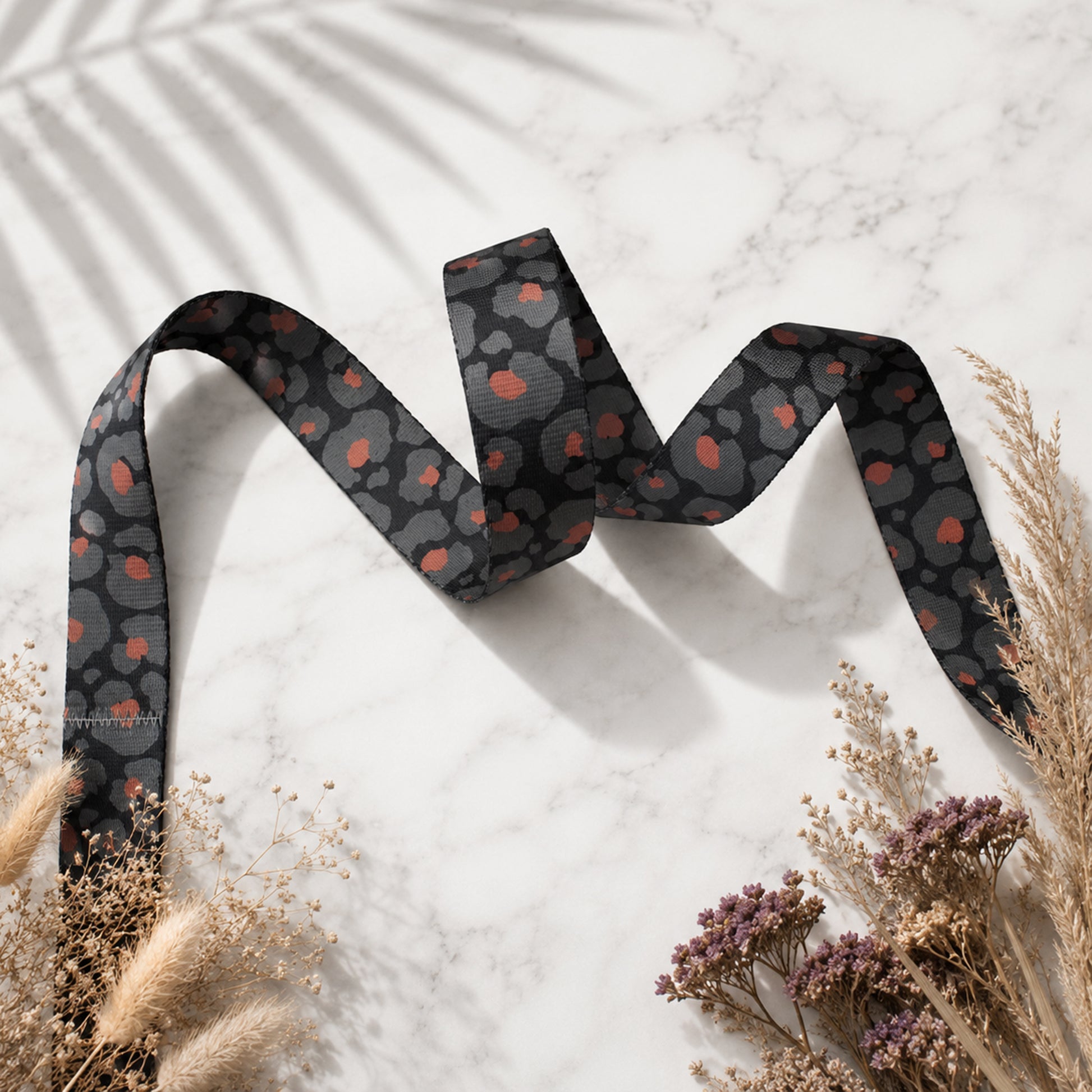 Black ribbon with red pattern on a light background with dried plants