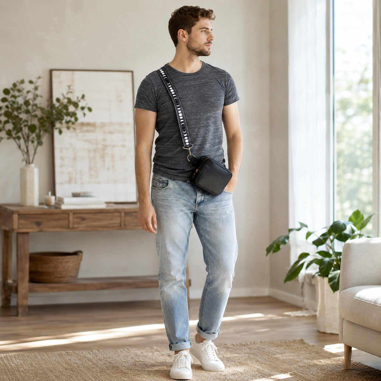 Man standing in a living room wearing a black crossbody bag