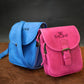Blue and pink bags with visible branding on a wooden surface and dark background