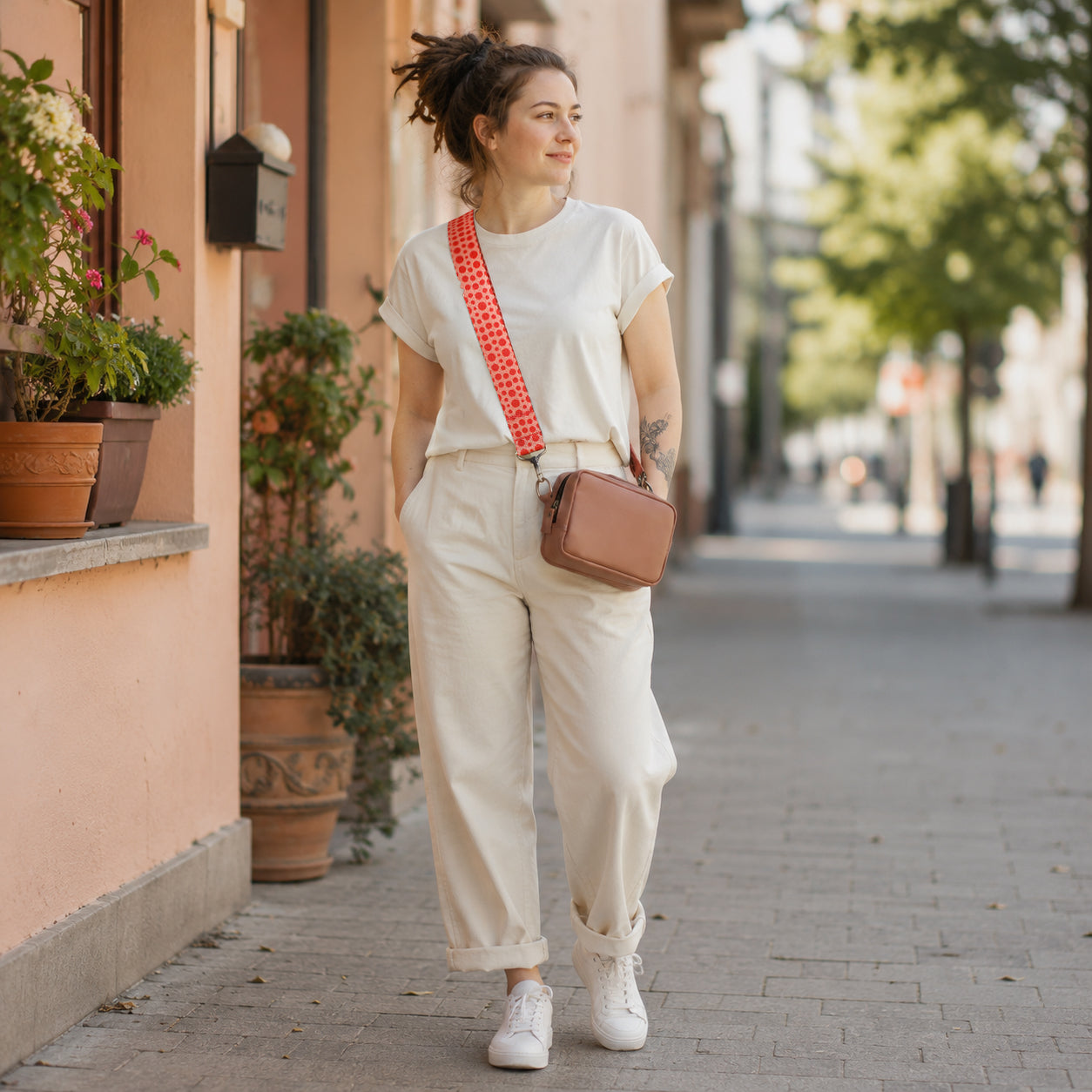 Woman walking on a sidewalk with a pink bag and white outfit