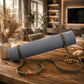 A rolled blue-gray yoga mat with an olive green carrying strap and a small tan brand patch reading EVA, displayed on a rustic wooden table in a warm, softly blurred living room setting.