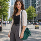 Woman walking on a city street holding a green bag