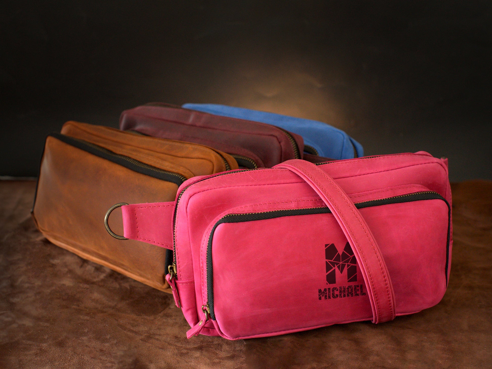 Multiple leather sling bags with monogram initials on textured surface