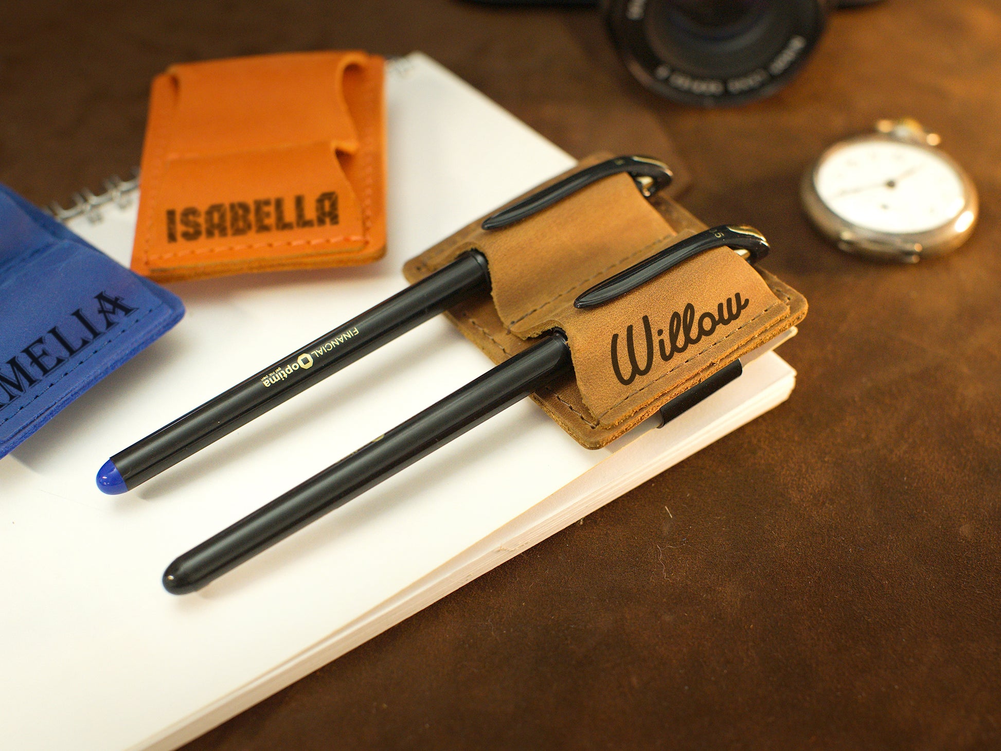 Multiple leather pen loops with monogram initials on textured surface