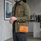 Person wearing a green coat with an orange crossbody bag in a modern interior setting