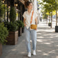 Woman walking on a sidewalk with plants and buildings in the background