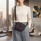 Woman holding a purple handbag in an office setting with large windows.