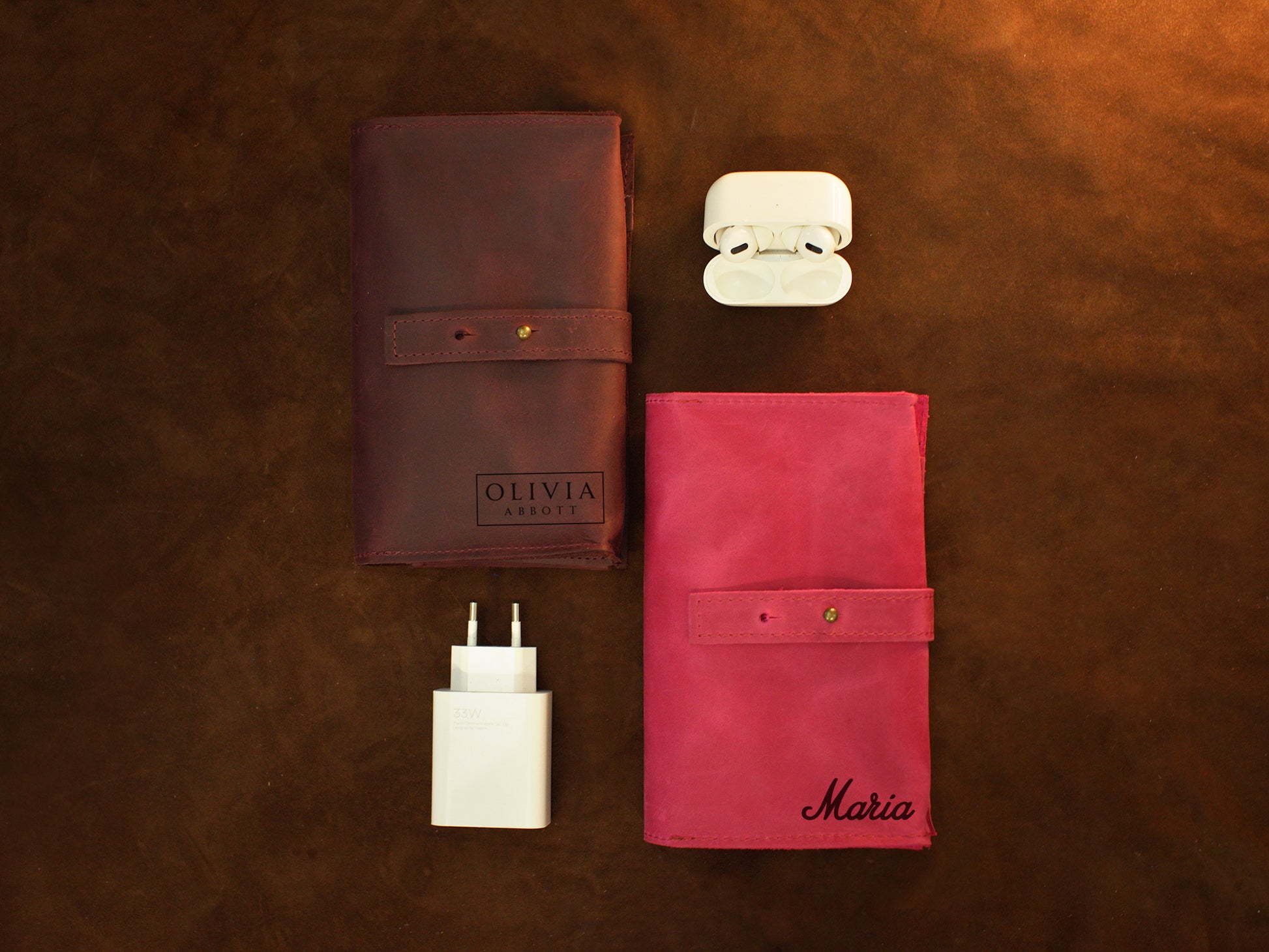 Multiple leather cable rolls with monogram initials on textured surface