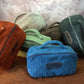 Set of colorful plush bags with visible branding on a textured surface.