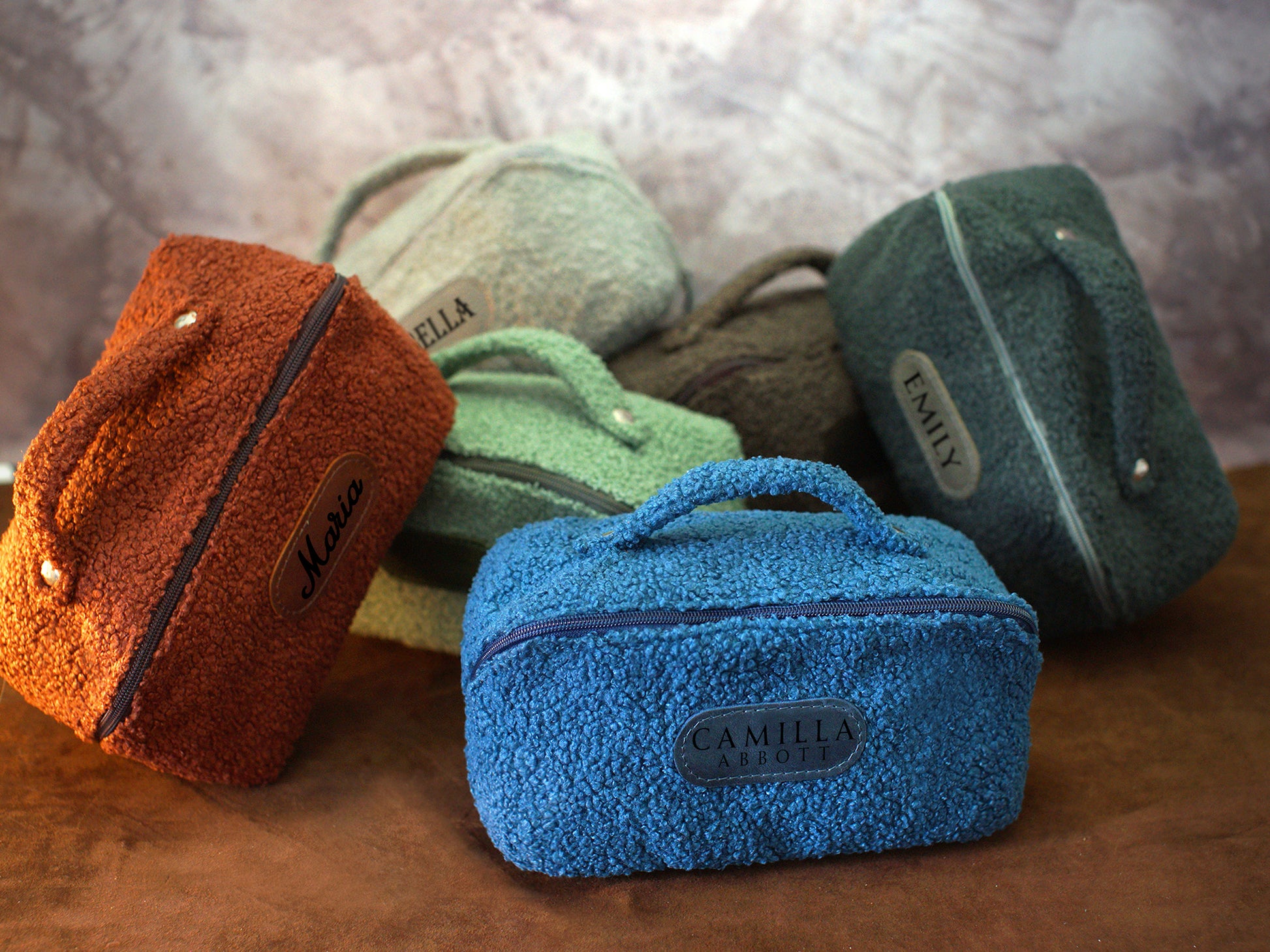 Set of colorful plush bags with visible branding on a textured surface.