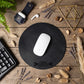 A round black mouse pad with a 'AUTO SERVICE' bar graphic in the center, styled in a flat-lay on a wooden desk with a white computer mouse, keyboard, leather wallet, and dried decorative grasses.