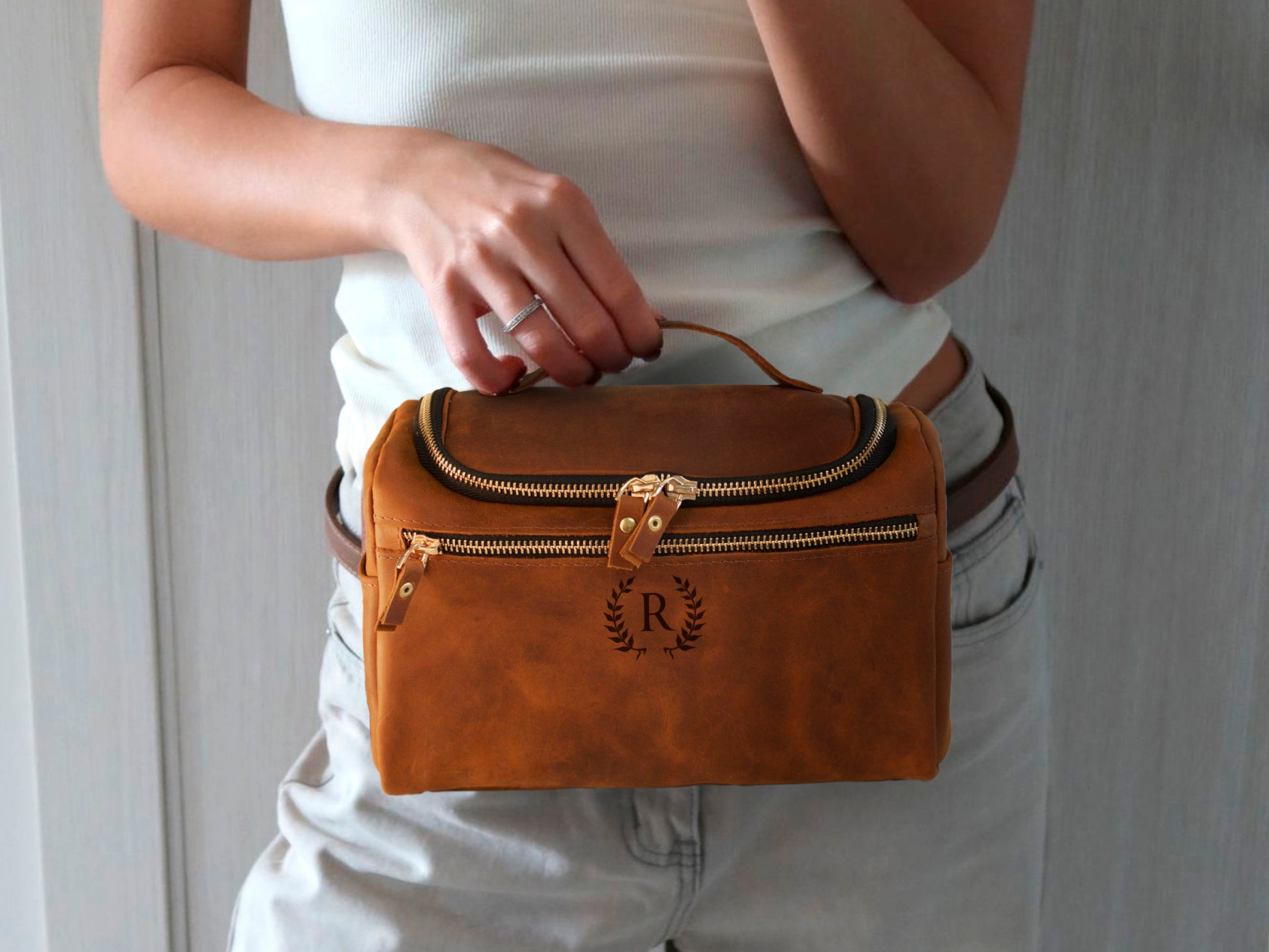 Person holding a brown leather handbag with a visible brand logo.