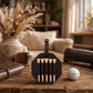 A dark brown leather golf accessory set displayed on a rustic wooden table, featuring a hexagonal holder with five wooden club tips and a leather strap, styled with a golf ball, notebook, and dried flowers in a warm indoor setting.
