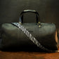 Green leather duffel bag with zebra pattern strap on a wooden surface