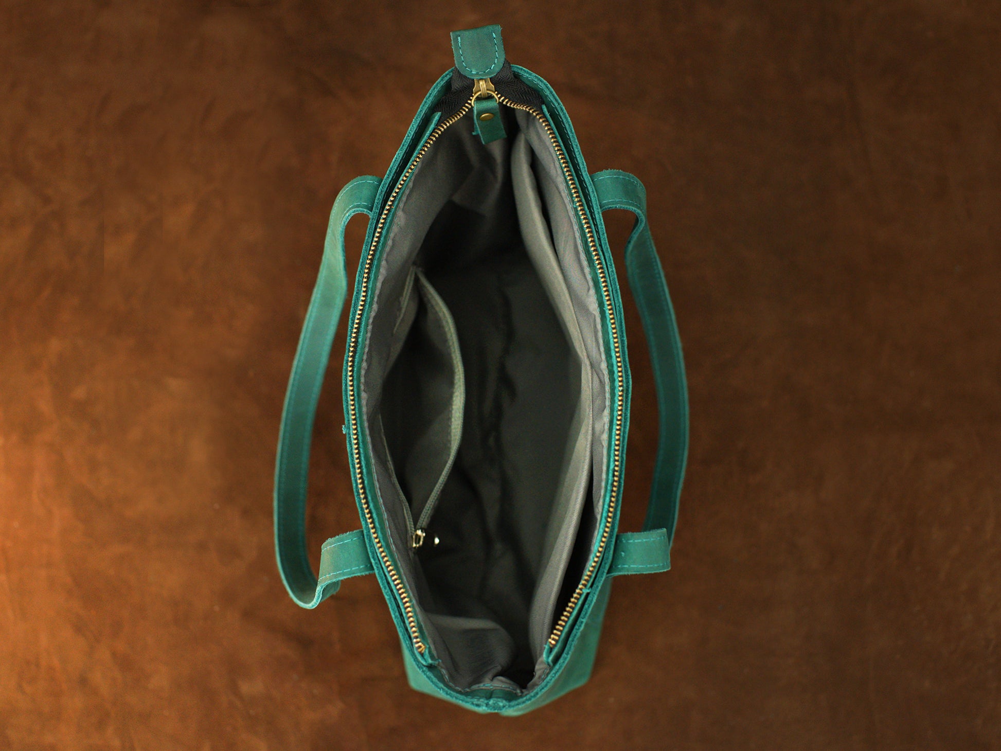 Green handbag with gold zipper on a brown background