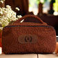Brown textured cosmetic bag with a logo on a blurred background