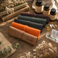 Four rolled leather journal covers in tan, orange, dark green, and plum purple are arranged on a rustic wooden table with vintage books, dried flowers, supplement bottles, and pills. One tan cover is personalized with the name 'Freddie' in black script.