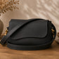 Black leather handbag on a wooden surface with a neutral background