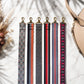 Set of patterned strap ends on a marble surface with a beige handbag.