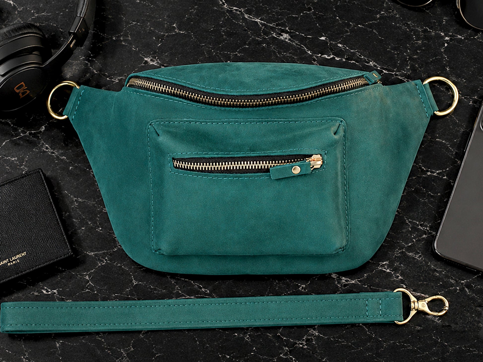 Emerald waist bag on a dark marble surface with a phone and wallet nearby
